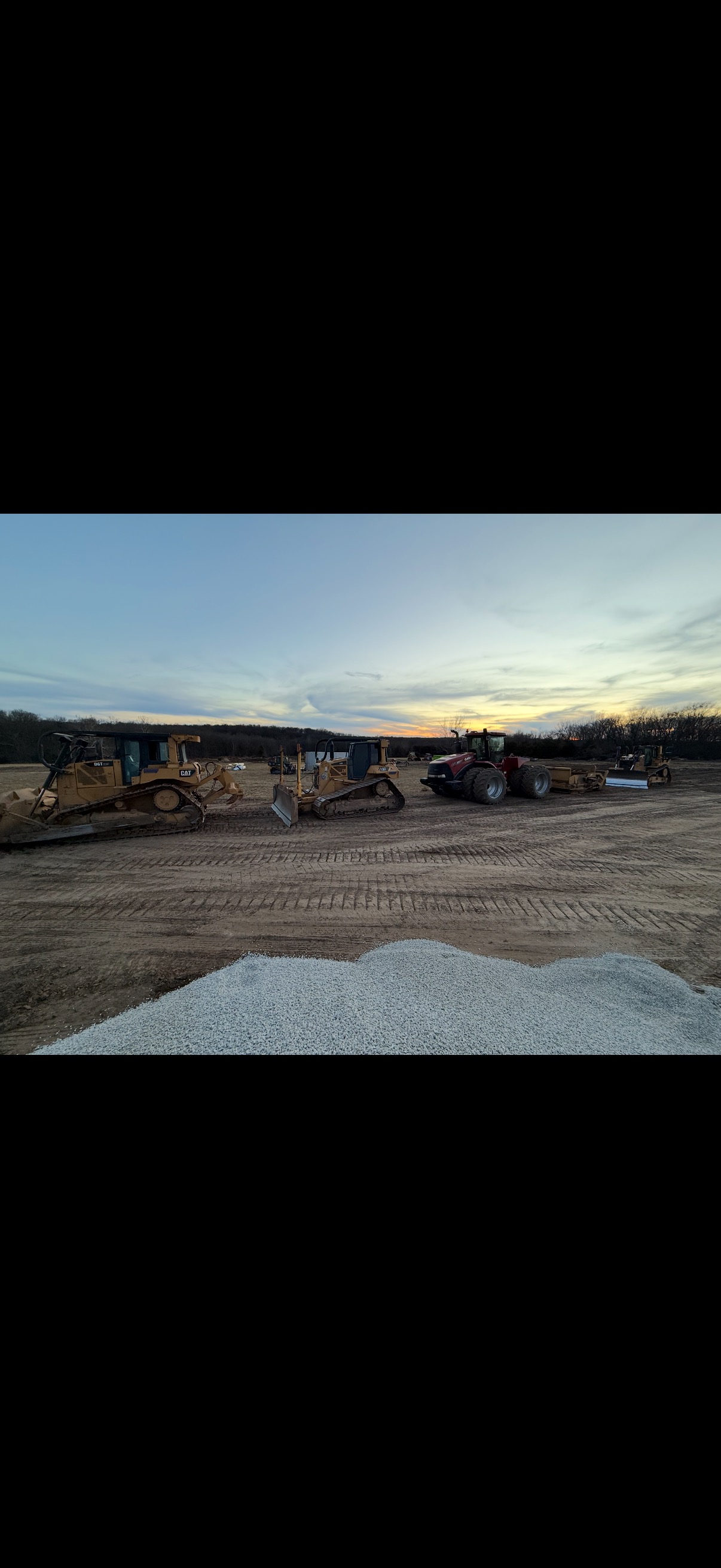 Bulldozers and scraper fleet lined up at sunset on a Windsor, MO job site Bulldozers and scraper fleet lined up at sunset on a Windsor, MO job site